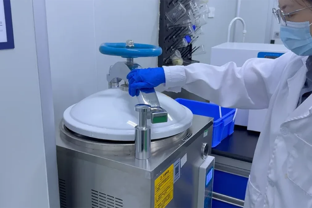 Technician operating stainless powder processing equipment in a controlled facility